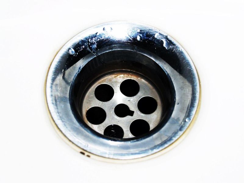 Desagüe cromado de un fregadero con gotas de agua