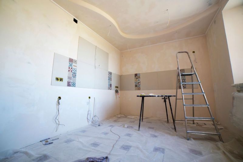 Sala en obra con escalera de tijera y paredes a medio acabar