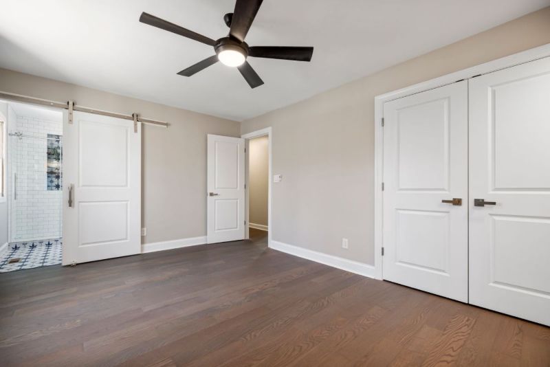Habitación vacía con suelo de madera y puertas blancas