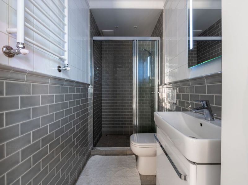 Baño con azulejos grises y ducha con mampara