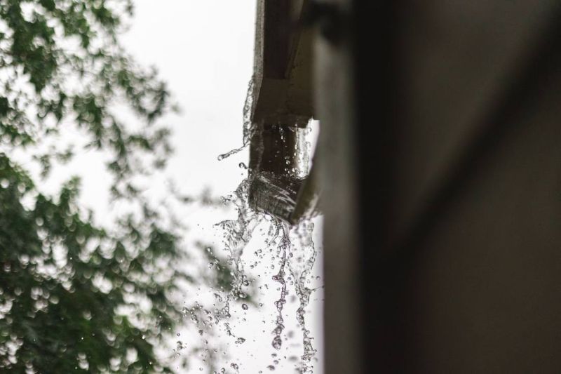 Acqua che cade da una grondaia in un giorno di pioggia
