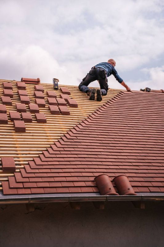 Arbeiter beim Wiederverlegen der Ziegel auf den Latten