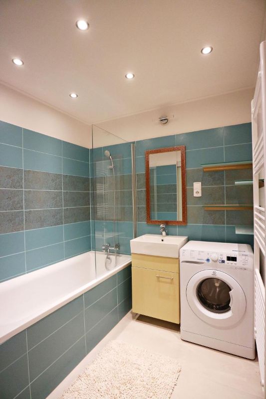 Baño con azulejos verdes y lavadora