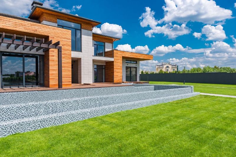 Fachada de cristal con jardín y césped