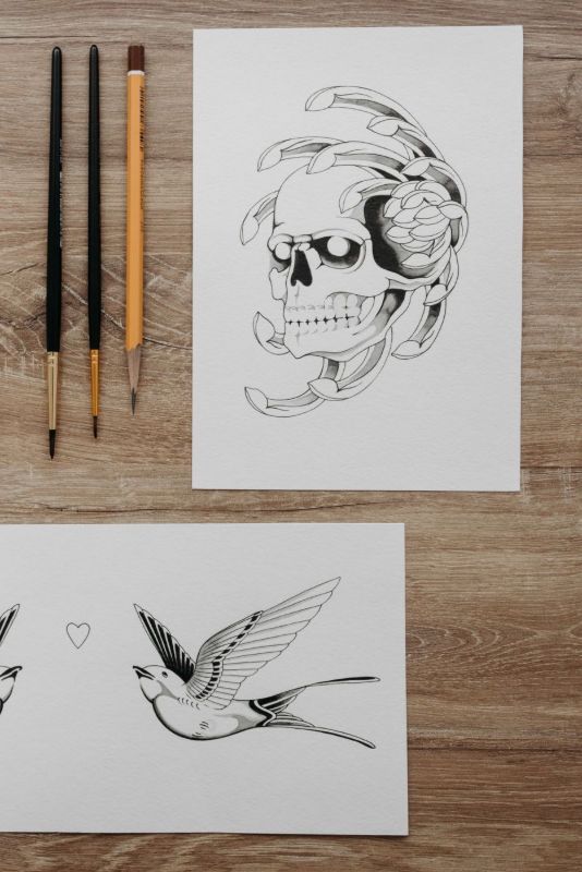 Flash drawings of a skull and swallows on paper, with brushes