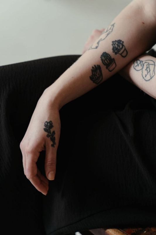 Arm with small black tattoos of flowers and hearts