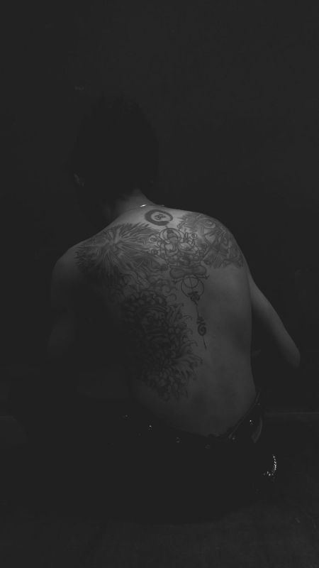 Tattooed back in low light, in black and white